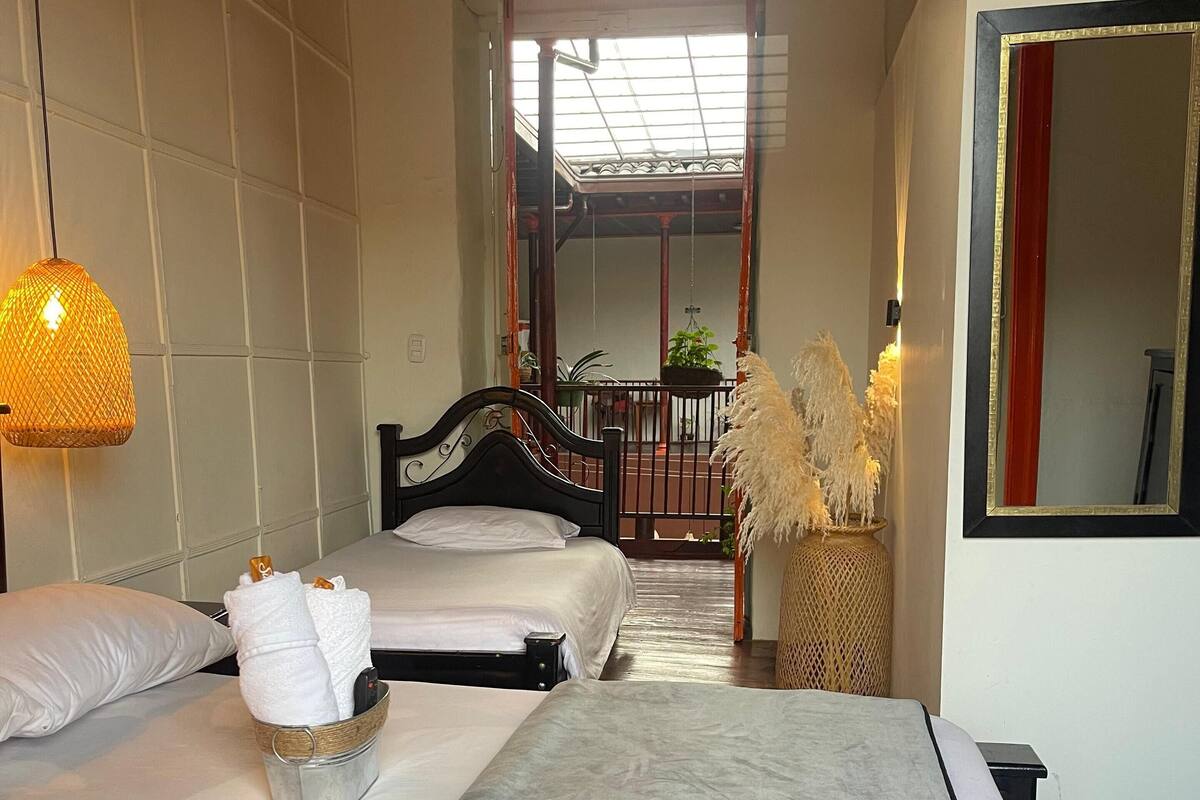 A hotel room with two beds, a large mirror, and a view of a balcony with plants.