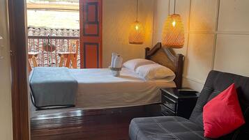 Un dormitorio con cama, sofá y balcón con sillas.