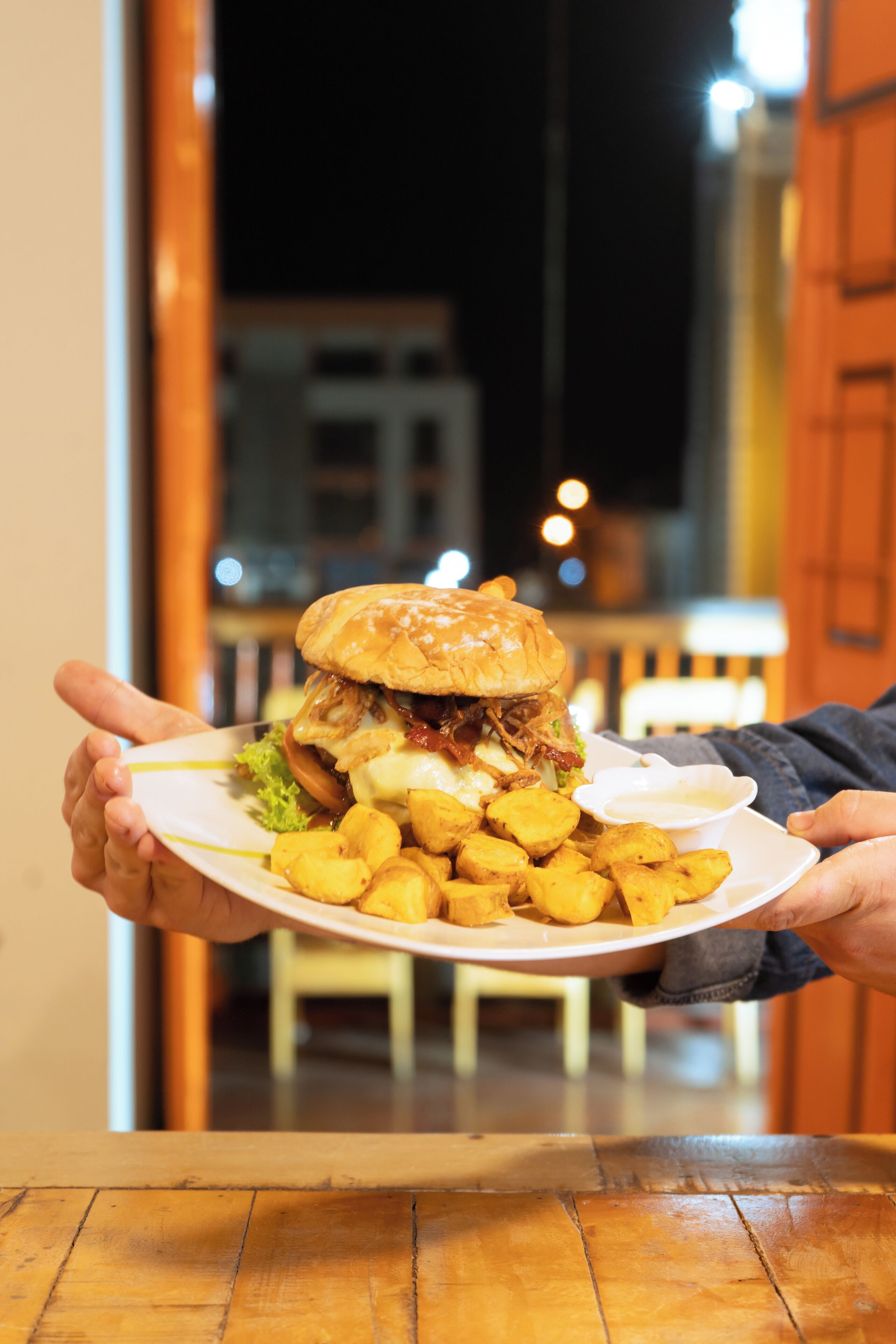 Une personne tenant une assiette avec un grand hamburger et des frites.