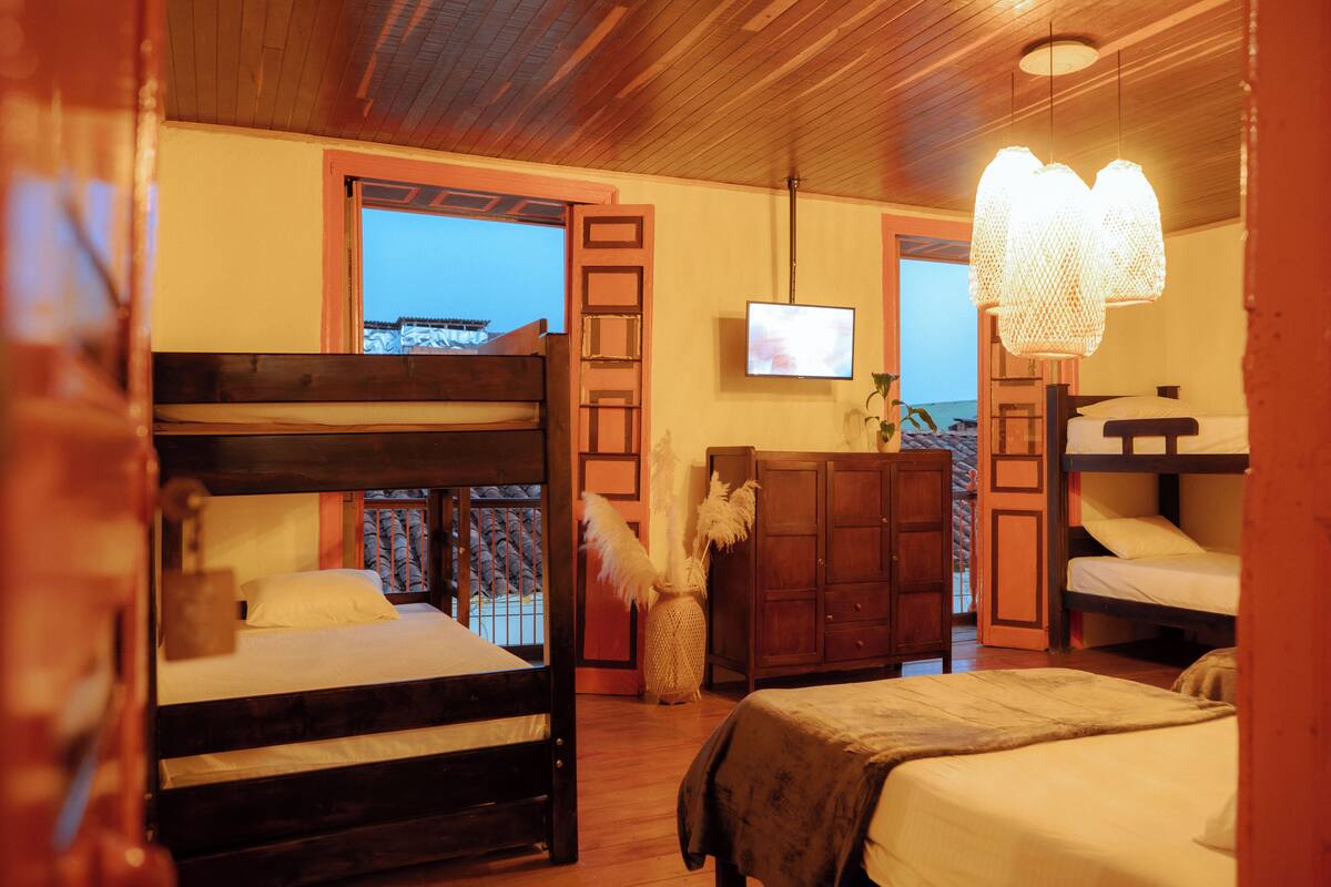A room with two bunk beds, a television, a wooden cabinet, and a decorative vase.