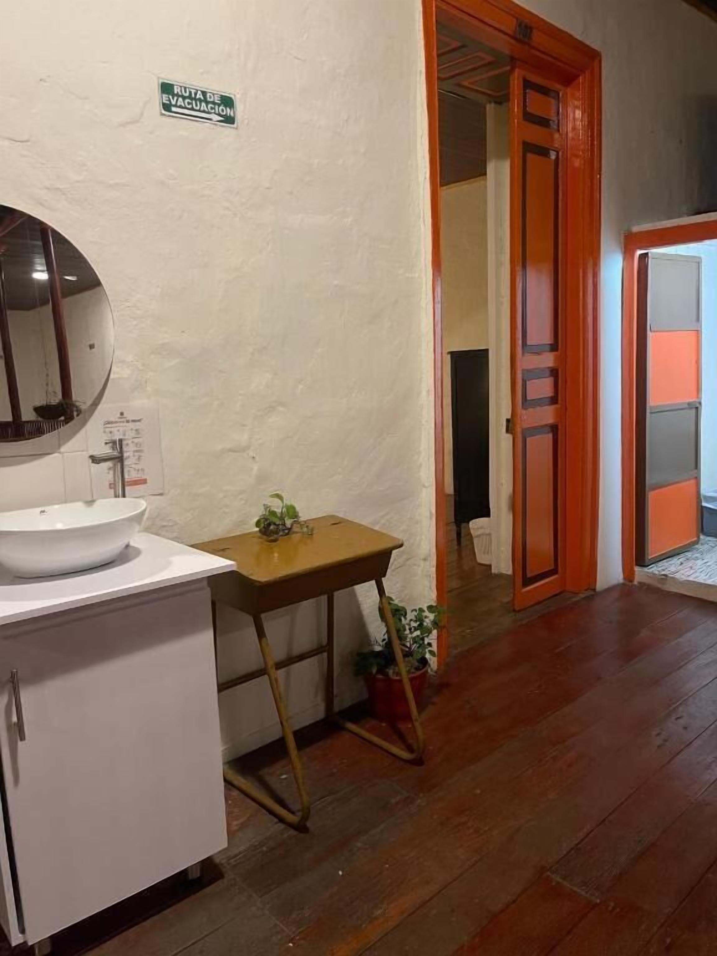 Bany amb un lavabo, mirall i una taula petita amb una planta.