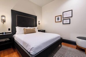 Een moderne hotelkamer met een groot bed, nachtkastje, wandlamp en lijstwerken.