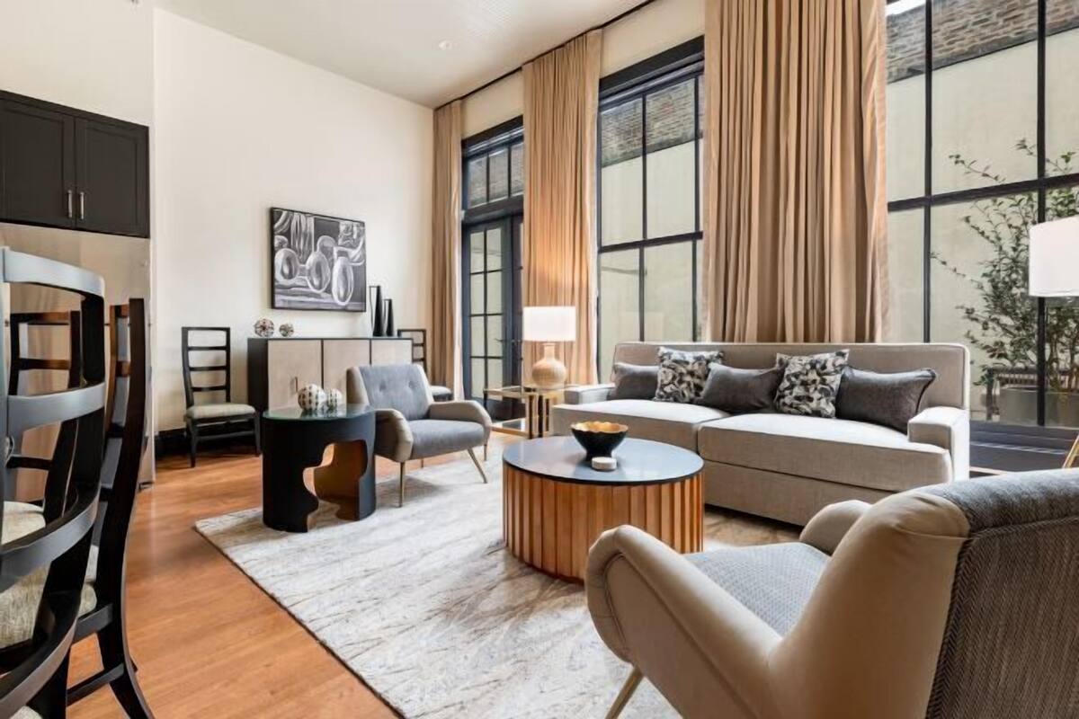 A modern living room with a sofa, chairs, a coffee table, and a dining area with a table and chairs.