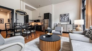 A modern living room with a round coffee table, a sofa, and a dining area with chairs and a table. - 3BR Group Haven + Private Patio Walk to French Quarter The Mayfair (New Orleans)