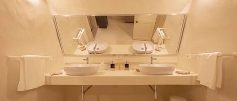 Un bagno moderno con due lavandini, uno specchio grande e un cestino.
