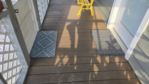 A wooden deck with two mats, a yellow bench, and a white lattice fence.