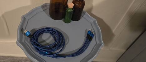A gray octagonal table with a blue coiled cable, two brown bottles with cork stoppers, and a green bottle with a cork stopper.