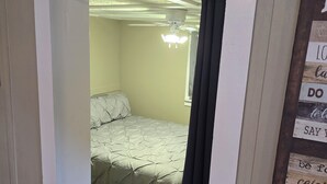 A room with a bed, a caution sign, a ceiling fan, and motivational wall art.