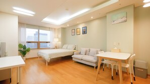 Une chambre d’hôtel moderne équipée d’un lit, d’un canapé, d’une table à manger et d’une petite poubelle.