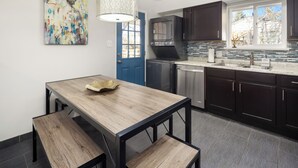Een moderne keuken met donkere kastjes, een houten eettafel en een blauwe deur.