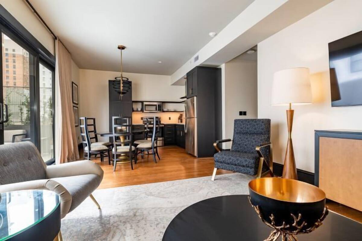 A modern living room with a dining area, a kitchen, and a large window.