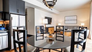 A modern kitchen with a central island, dark cabinetry, and a dining area with a round table and chairs.