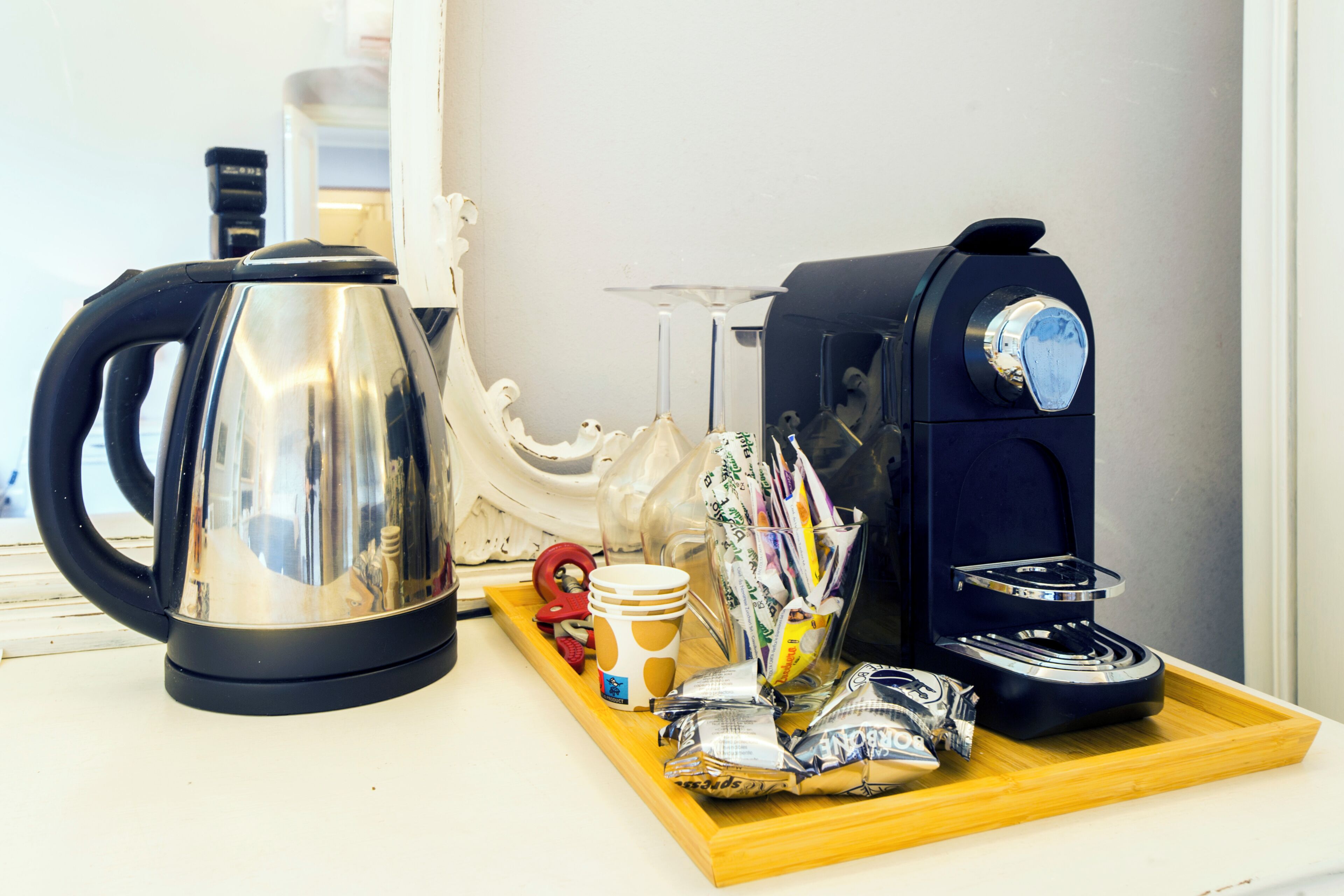 Une machine à café, une bouilloire et un plateau avec des tasses et des en-cas sur une table.