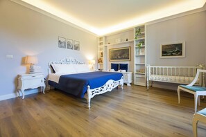 A bedroom with a bed, bedside tables, a nightstand, a chair, a shelf with decorative items, and a painting on the wall. - Mare e Monti (Genoa)
