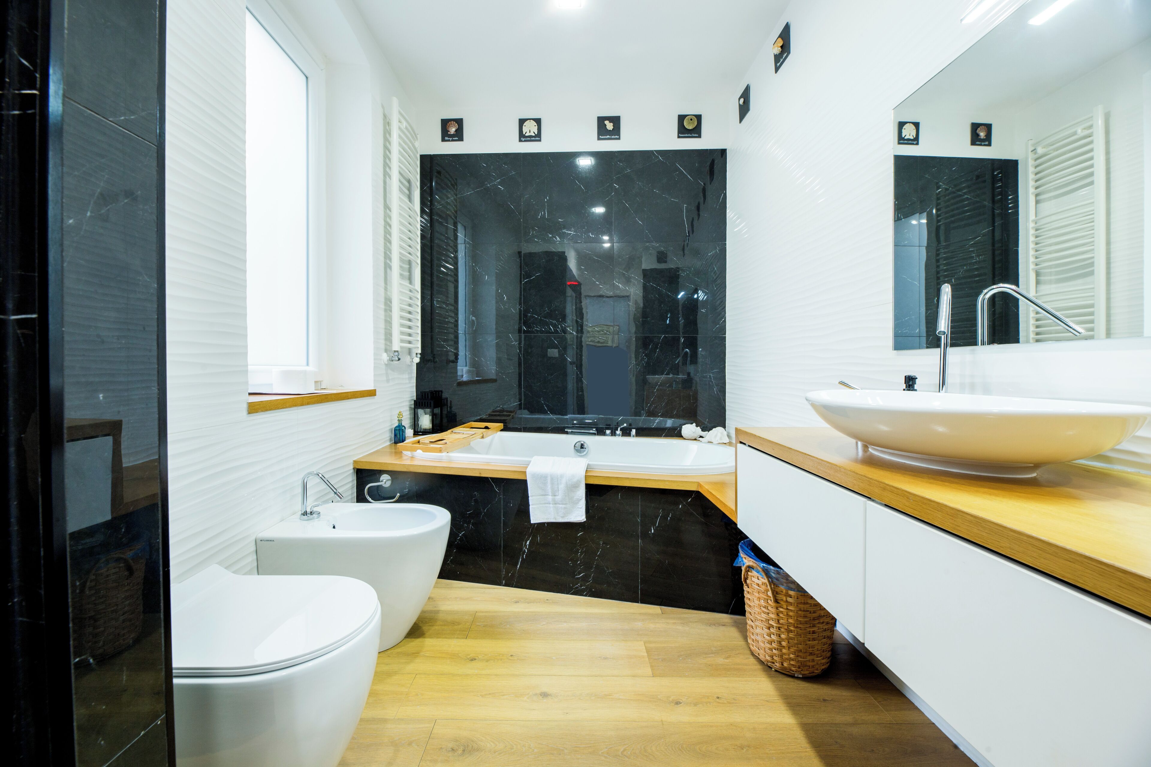 A modern bathroom with a bathtub, a large mirror, a sink, and a toilet.