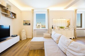 A modern living room with a sofa, television, and a view of a cityscape through large windows. - Mare e Monti (Genoa)