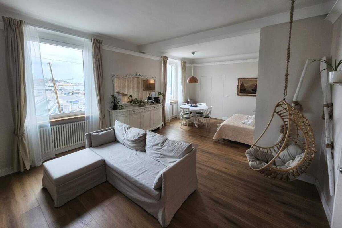A modern hotel room with a sofa, a hanging chair, a dining area, and a view of the city.