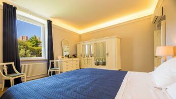 Une chambre d’hôtel avec un grand lit, une commode, un miroir, une chaise et une fenêtre avec des rideaux.