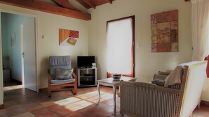 Una sala de estar con un sofá, un televisor, una mesa con un tazón y un radiador.