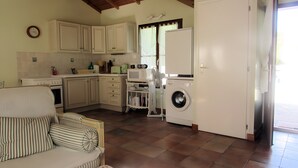 Una cocina compacta con lavadora, una zona de comedor con sofá y suelo de baldosas.