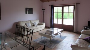 A living room with a glass coffee table, a sofa, a dining table with chairs, a floor lamp, and a window with curtains. - Lavender Cottage, Heated Pool, Between Countryside and Sea, Quiet Marais Poitevin Retreat (Nalliers)