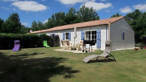 A house with a patio, outdoor furniture, and a barbecue grill. - Lavender Cottage, Heated Pool, Between Countryside and Sea, Quiet Marais Poitevin Retreat (Nalliers)