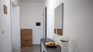 A modern bathroom with a wooden vanity, a mirror, and a vase with flowers. - Sea Apartment (Nocera Terinese)