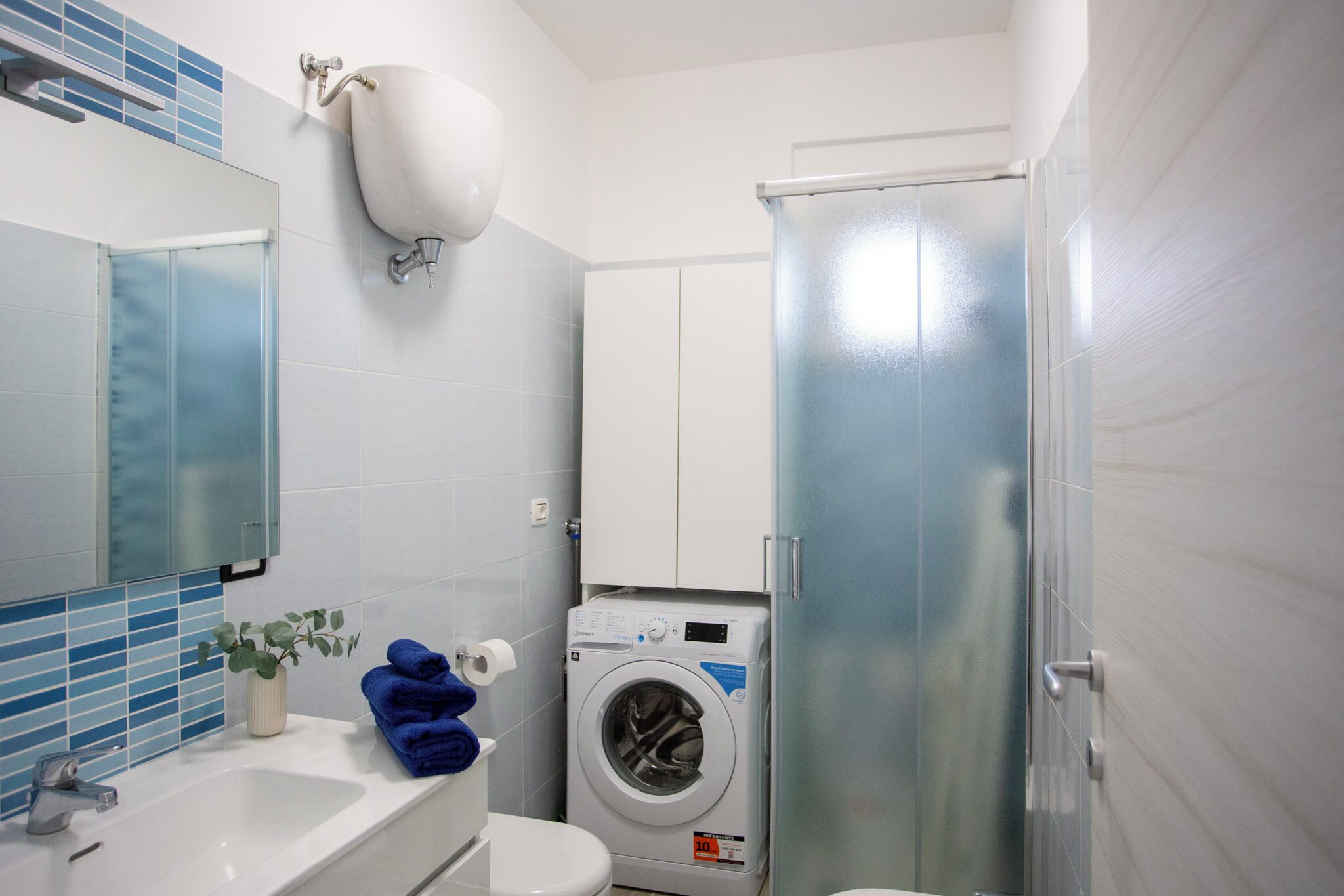 A compact bathroom with a white sink, a washing machine, and a toilet.