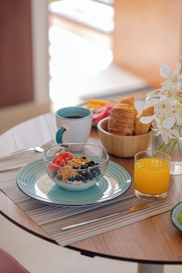 Une table de petit-déjeuner avec un bol de céréales, un verre de jus d’orange et une tasse de café.