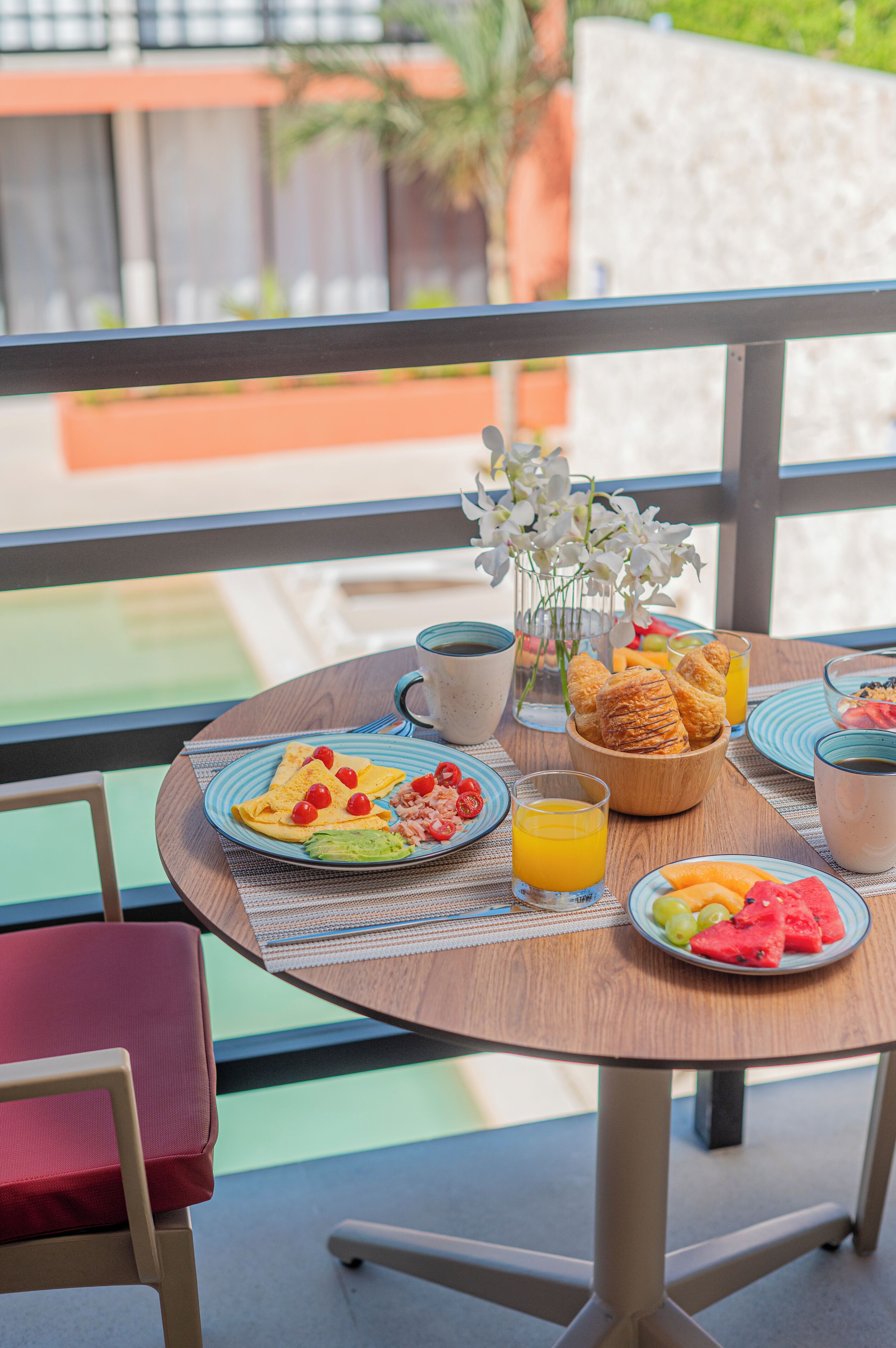 Una mesa de desayuno con platos de comida, un bol de pasteles y un jarrón de flores.