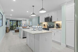 A modern kitchen with white cabinetry, a central island, pendant lighting, and a large window. - Pointe Santo A2 | Fabulous Beach View Paradise at Pointe Santo 2BR/den/2BA (Sanibel Island)