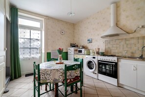 Cozinha compacta com área de jantar, equipada com máquina de lavar, micro-ondas e fogão.