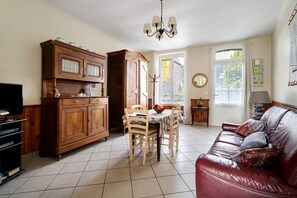 Sala de estar com sofá de couro, mesa de jantar de madeira e aparador para TV.