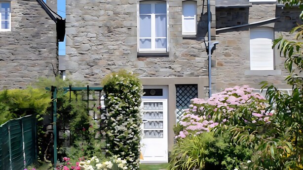 A stone building with a white door, a small garden with flowers, and a green bench. - Holiday Home “Les Flots Bleus Cancale” with Private Terrace, Garden & Wi-Fi (Cancale)