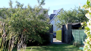 A garden pathway leading to a house with a green fence and a bench. - Holiday Home “Les Flots Bleus Cancale” with Private Terrace, Garden & Wi-Fi (Cancale)