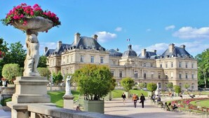 A large, historic building with classical architecture, a central courtyard, and a fountain with flowers. - Sevres - Bright 2-bedroom near Bon Marché (Paris)