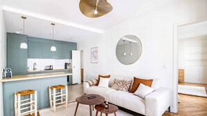 A modern apartment with a kitchen, a living area with a sofa and coffee table, and a dining area with stools. - Sevres - Bright 2-bedroom near Bon Marché (Paris)