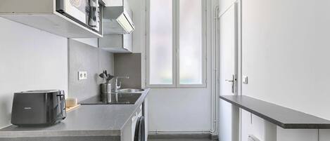 Una cocina compacta con lavadora, tostadora y un lavamanos pequeño.