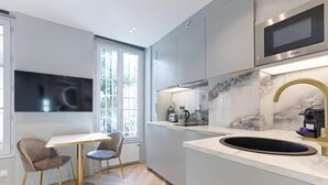 Een moderne keuken met een groot schiereiland, een ingebouwde magnetron en een raam dat voor natuurlijk licht zorgt.