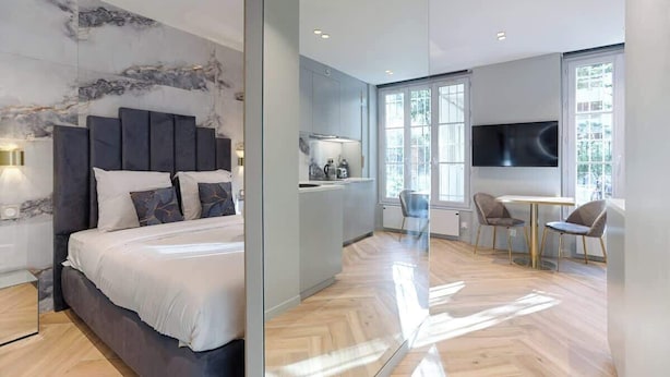 Een moderne hotelkamer met een groot bed, een kitchenette en een eethoek met een televisie.