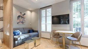 Een moderne woonkamer met een bank, een salontafel, en een eetgedeelte met stoelen en een tafel.