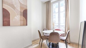 Un comedor con una mesa redonda, cuatro sillas y un cuadro abstracto grande en la pared.