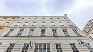 Un edificio de varios pisos con estilo arquitectónico clásico, que presenta ventanas regularmente distribuidas y barandillas decorativas.
