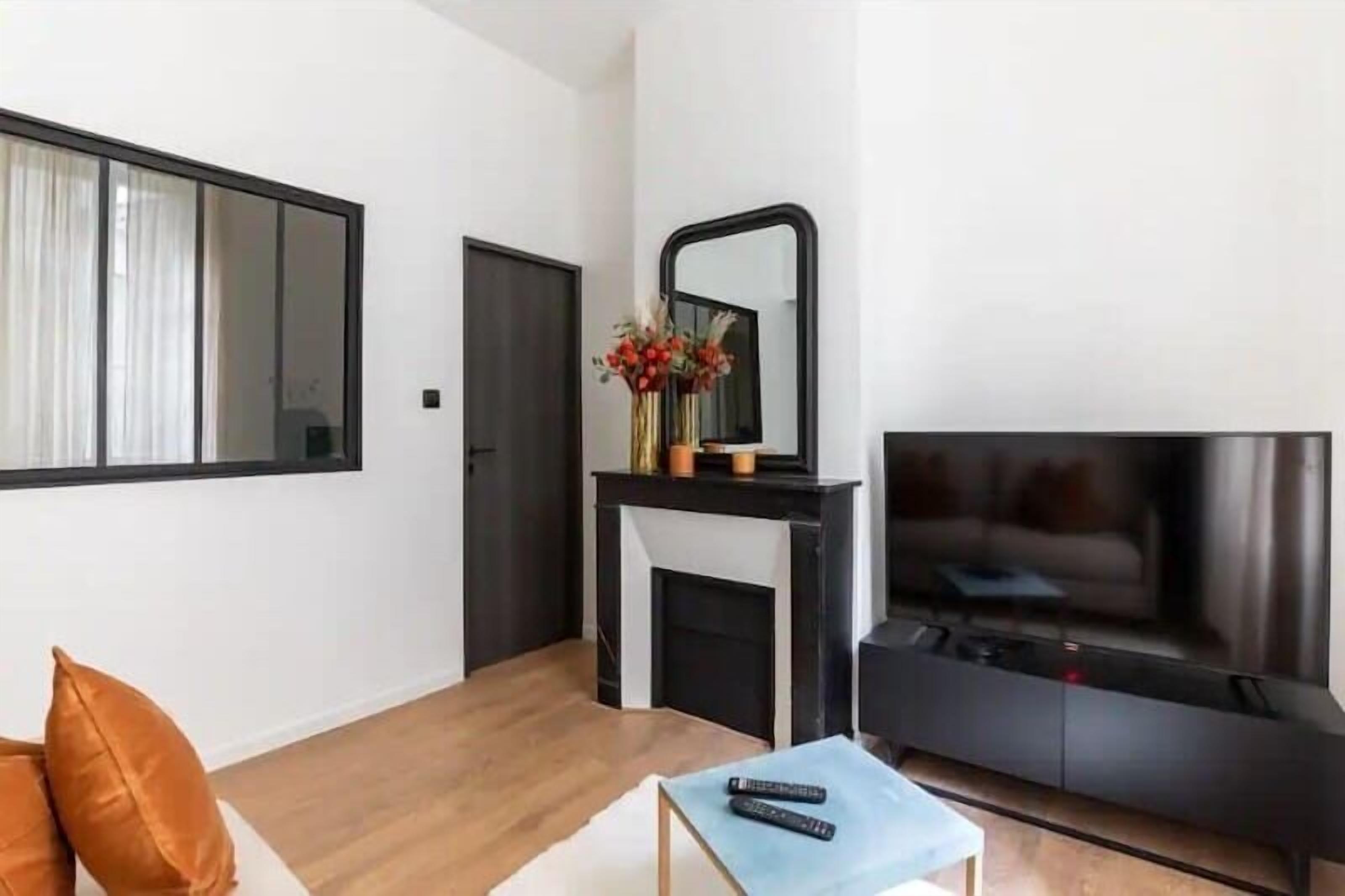 Ein modernes Wohnzimmer mit Kamin, einem großen Spiegel, einem Fernseher und einer Couch.