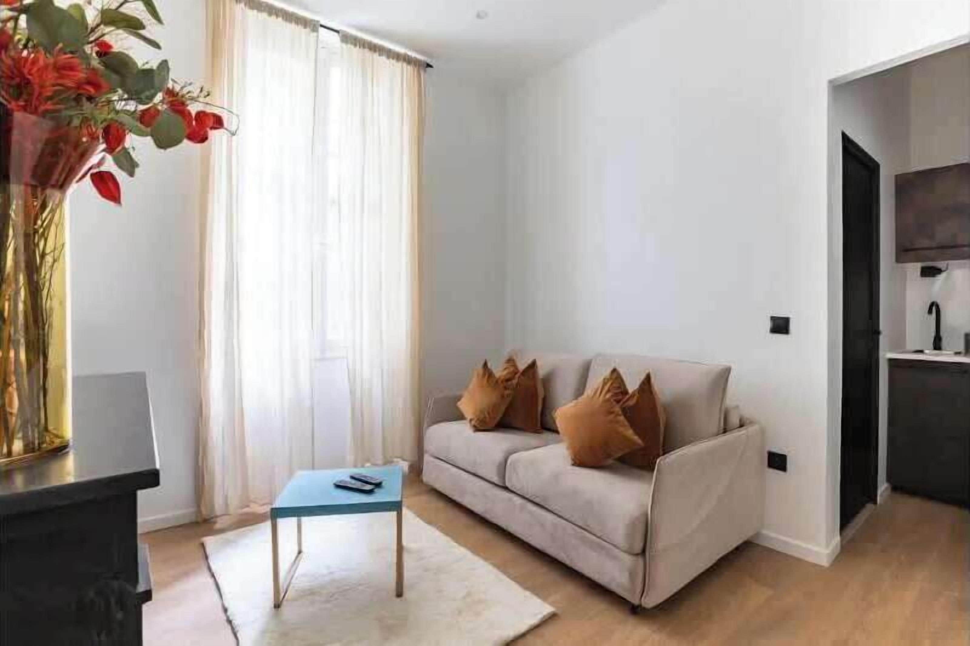 A modern living room with a sofa, a coffee table, and a vase of flowers.