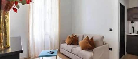 A modern living room with a sofa, a coffee table, and a vase of flowers.
