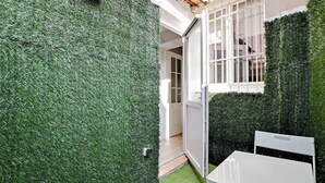 A small, enclosed outdoor space with artificial grass, a white table, and a chair. - Appartement cosy avec jardin proche de République (Paris)