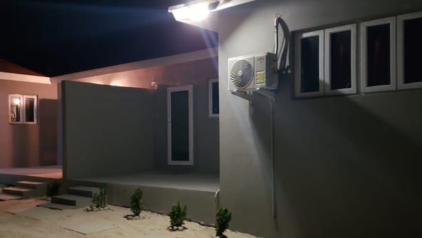 Un edificio con techo plano, un pequeño porche y un equipo de aire acondicionado instalado en la pared.