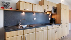 A modern kitchen with wooden cabinets, a stainless steel sink, and a built-in microwave. - Apartment 'Siglgut Laura' with Mountain View, Shared Terrace and Wi-Fi (Tarsch)