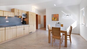 A modern kitchen with wooden cabinets, a microwave, and a dining area with a table and chairs. - Apartment 'Siglgut Laura' with Mountain View, Shared Terrace and Wi-Fi (Tarsch)